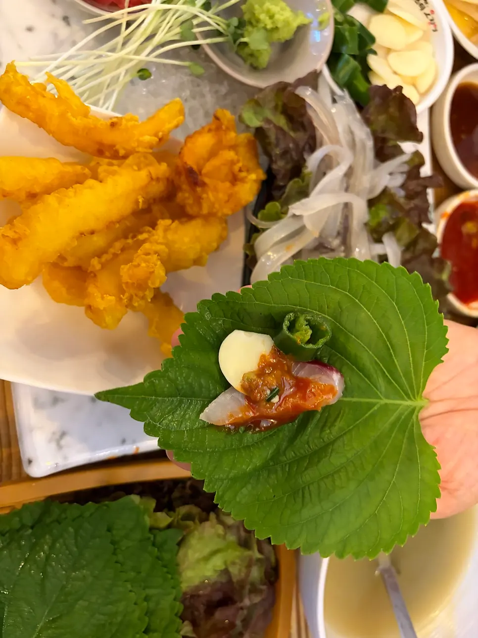 A bite of sashimi wrapped in perilla leaf