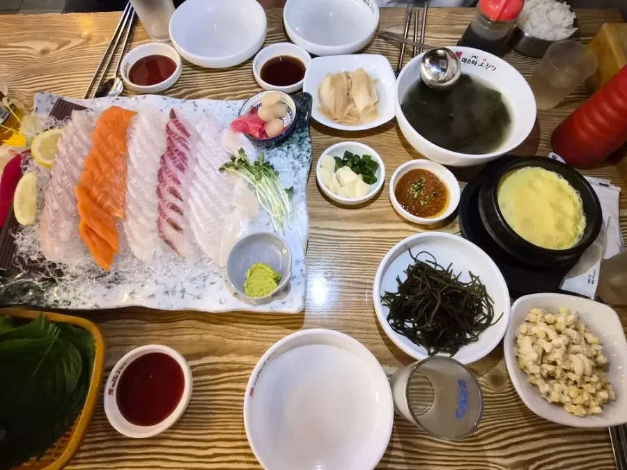 A piece of sashimi with perilla leaf and ssamjang and soy sauce