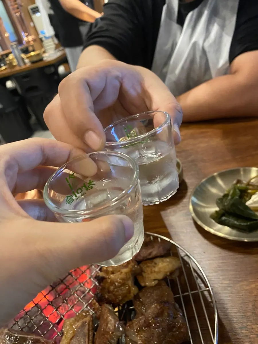 Soju glasses set beside the grilled meat