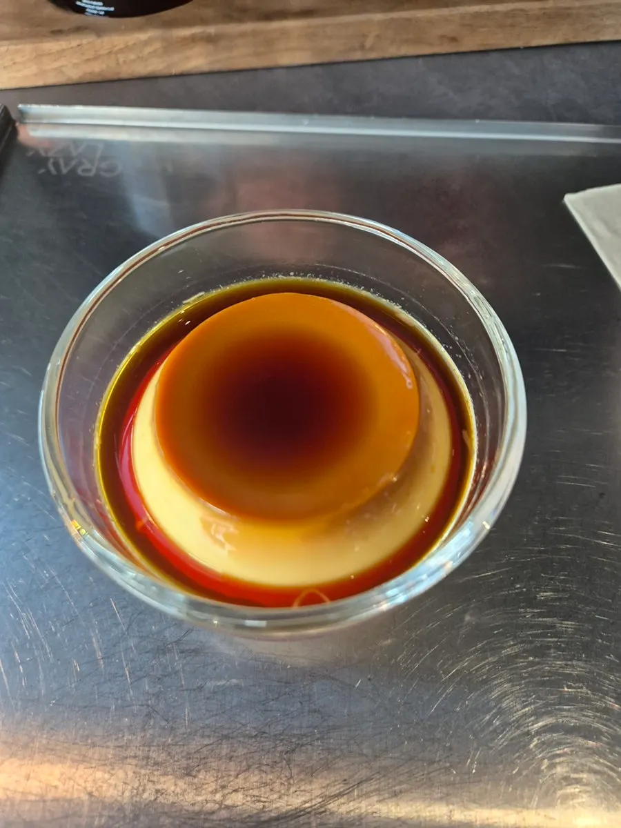 Iced coffee poured over jumbo ice cubes alongside handmade custard pudding