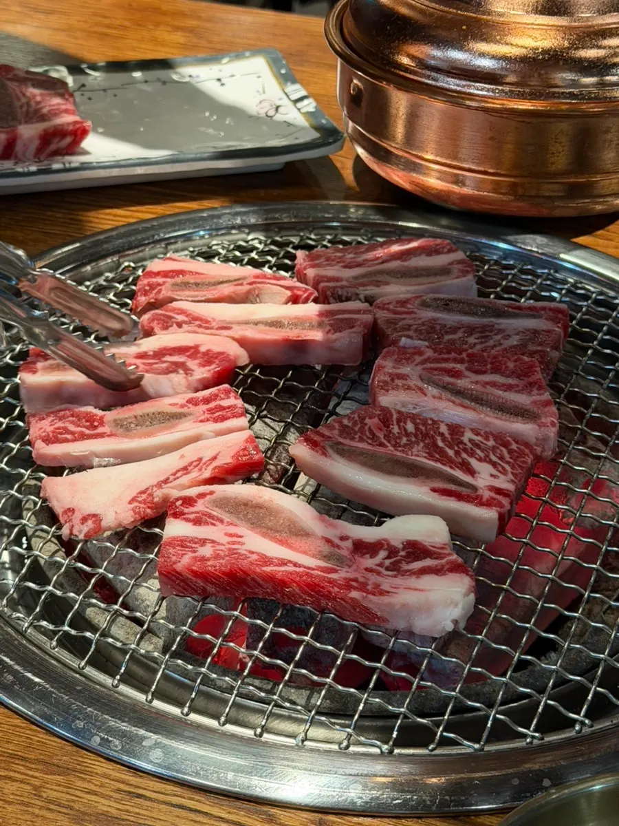직원이 참숯 불판에 생갈비를 굽는 모습