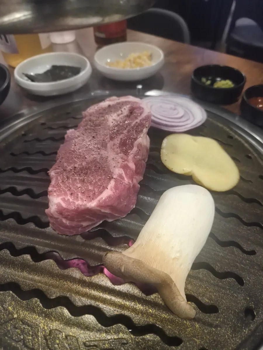 Staff member grilling pork neck on the tabletop grill