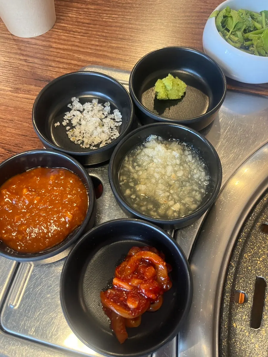 Side dishes of pickled onion, shredded green onion salad, and myeongi namul