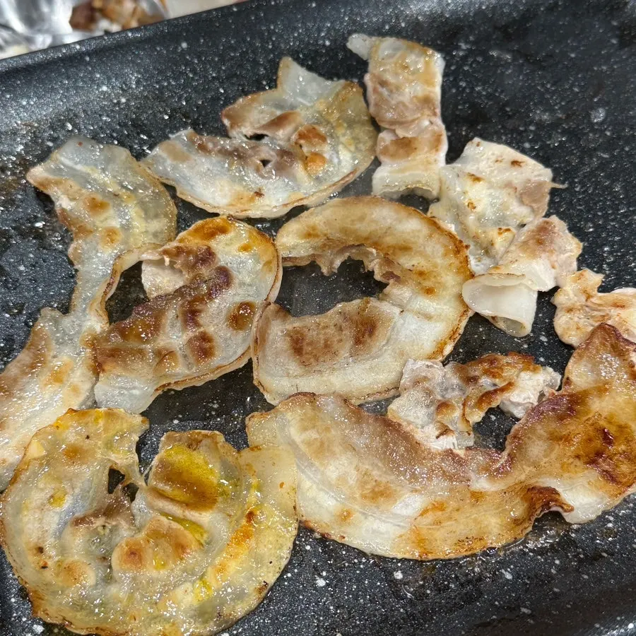 불판에 구워지는 대패삼겹살과 김치, 콩나물