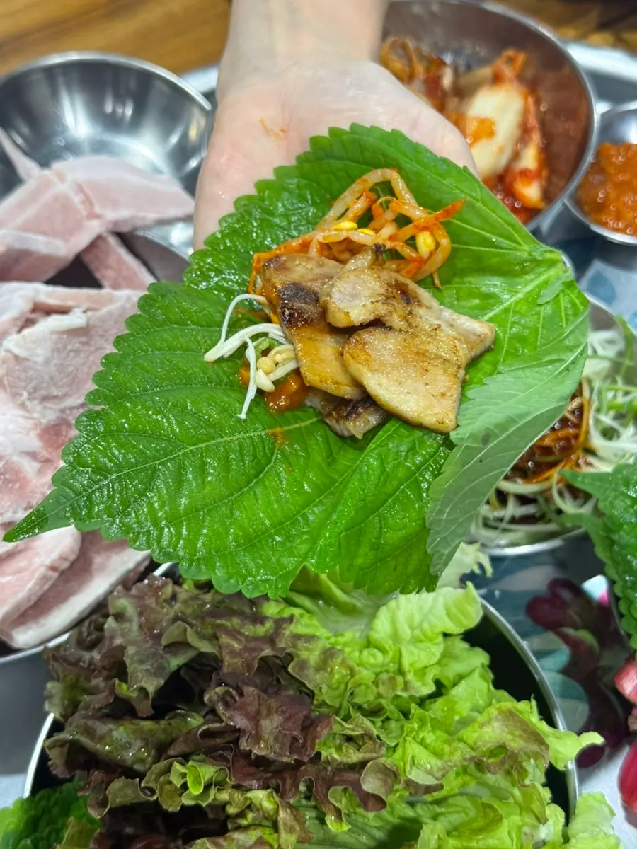 A bite of grilled meat piled on a lettuce leaf