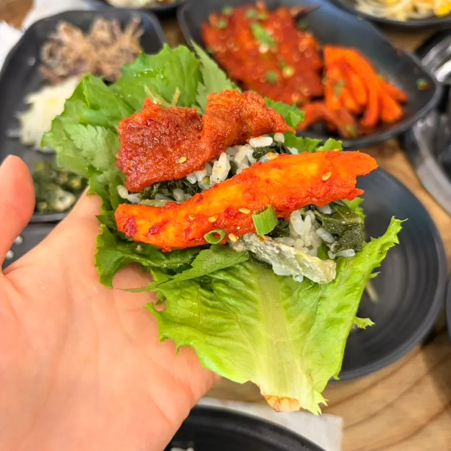 A lettuce wrap filled with meat and side dishes