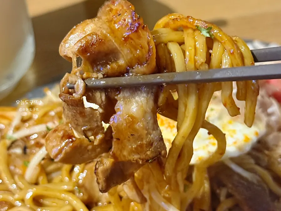 A bite of pork belly yakisoba mixed with egg yolk