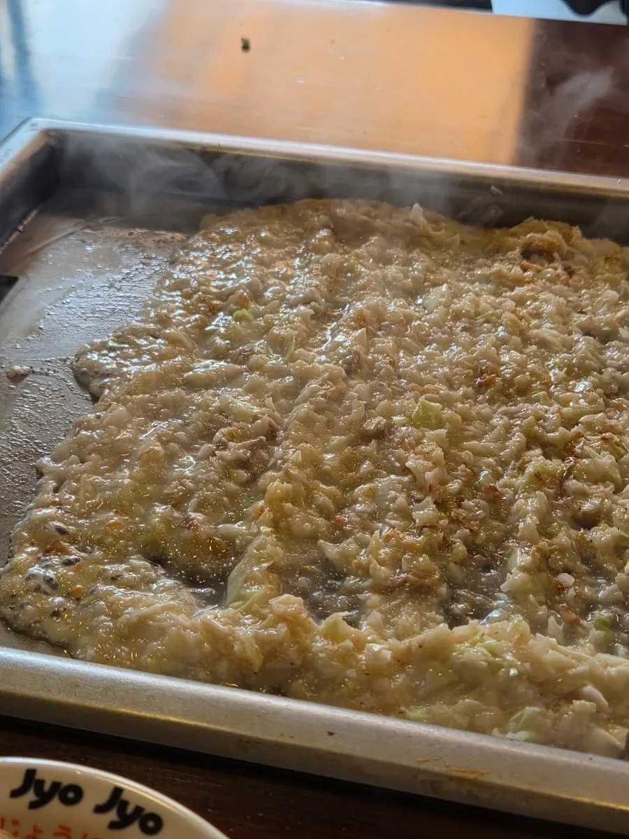 Mentaiko monjayaki being spread out and cooked on the griddle