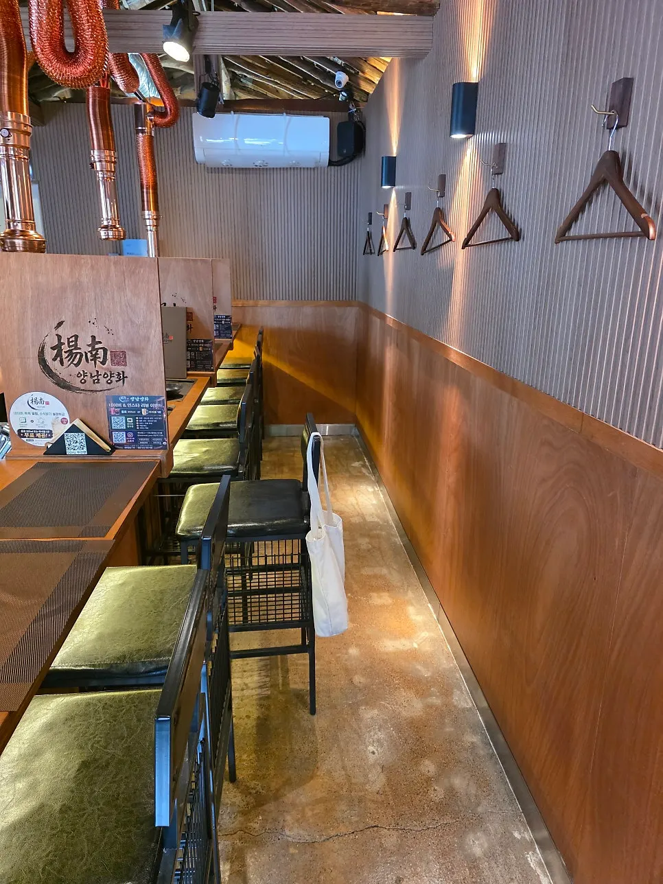 Interior bar table under wooden rafters with a brass hood