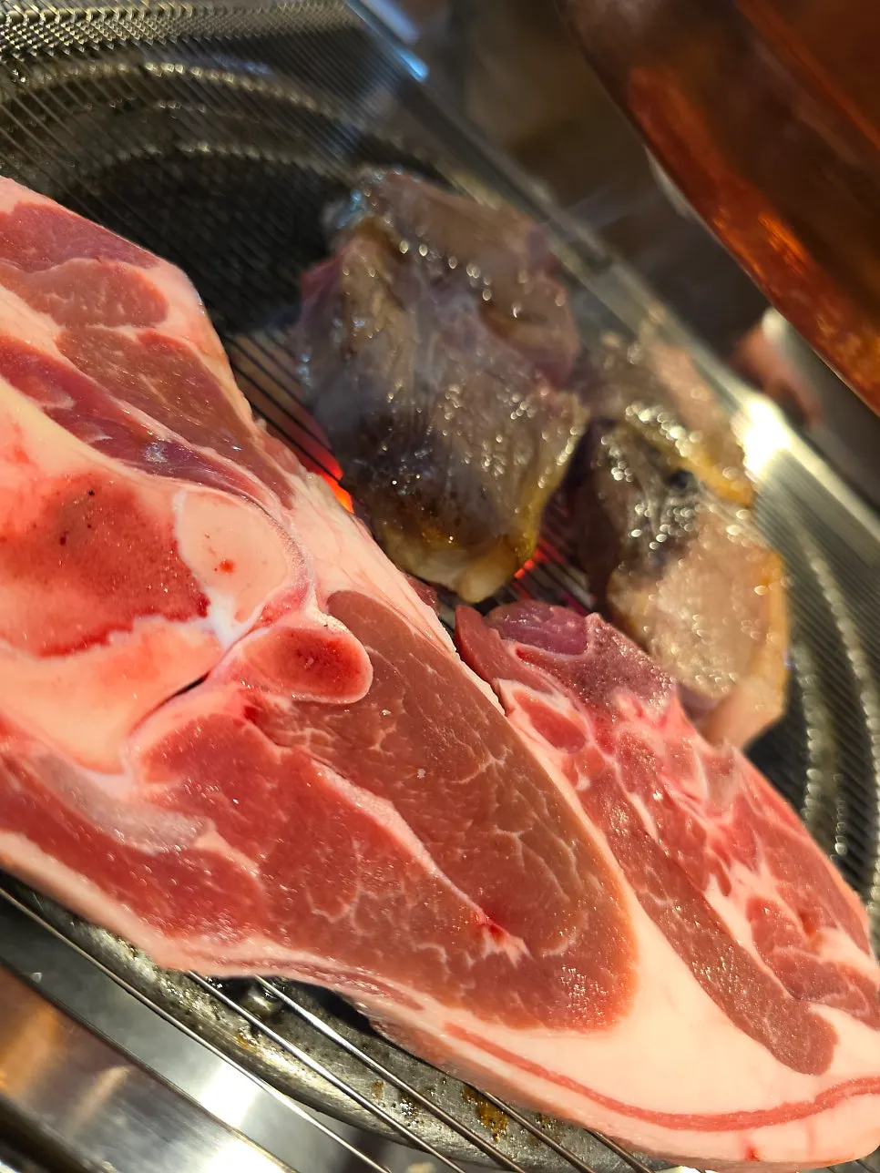 Lamb grilling alongside foil-wrapped vegetables
