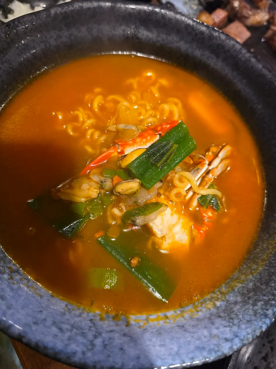 A bowl of seafood ramyeon with crab and mussels