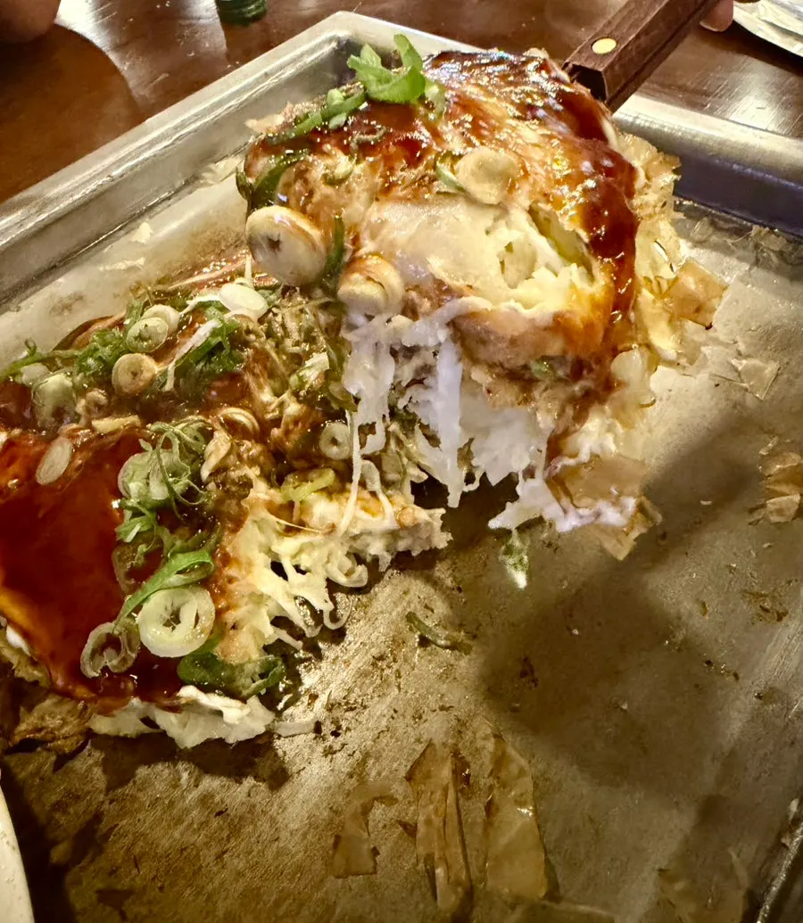 Finished okonomiyaki topped with sauce and green onion