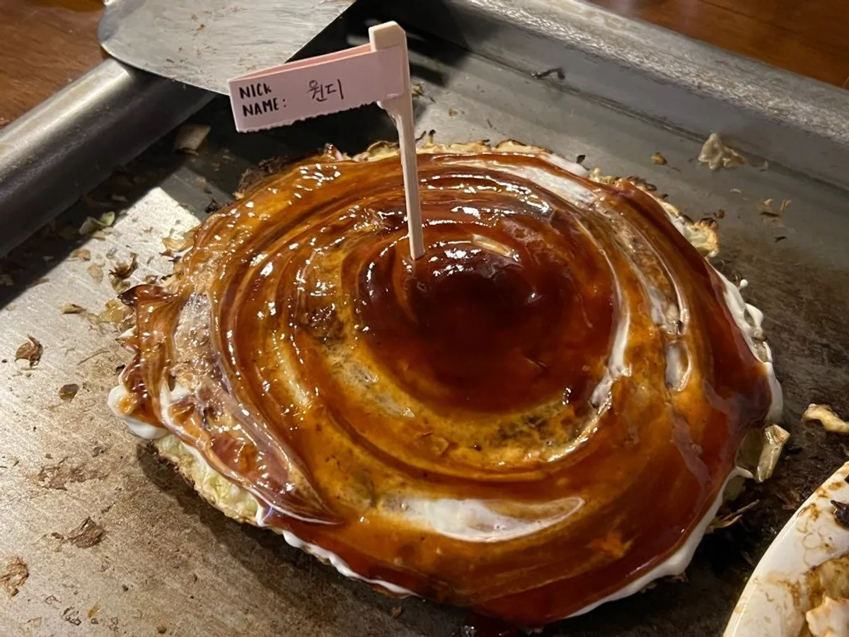 Okonomiyaki topped with sauce, mayo, and a flag