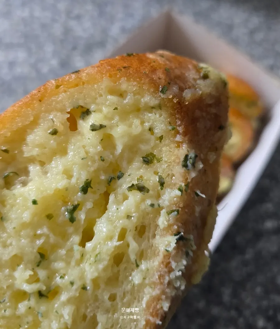 A piece of Munhwa Bakery's garlic bread picked up by hand