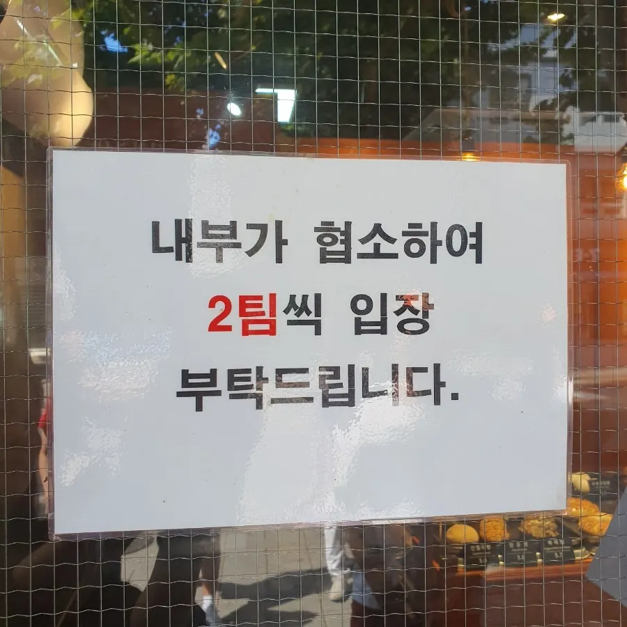 Store entrance with a sign asking for two parties at a time