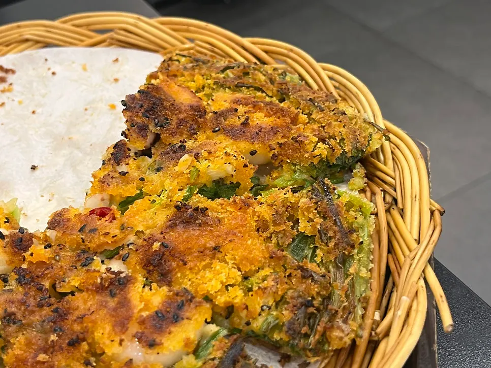 A piece of seafood pajeon picked up with chopsticks