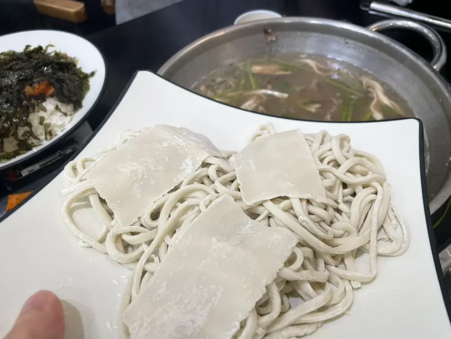 Adding kalguksu noodles into the broth to cook