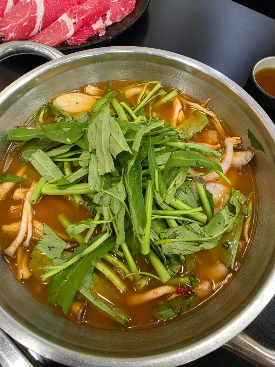 Minari and mushrooms added to the red broth