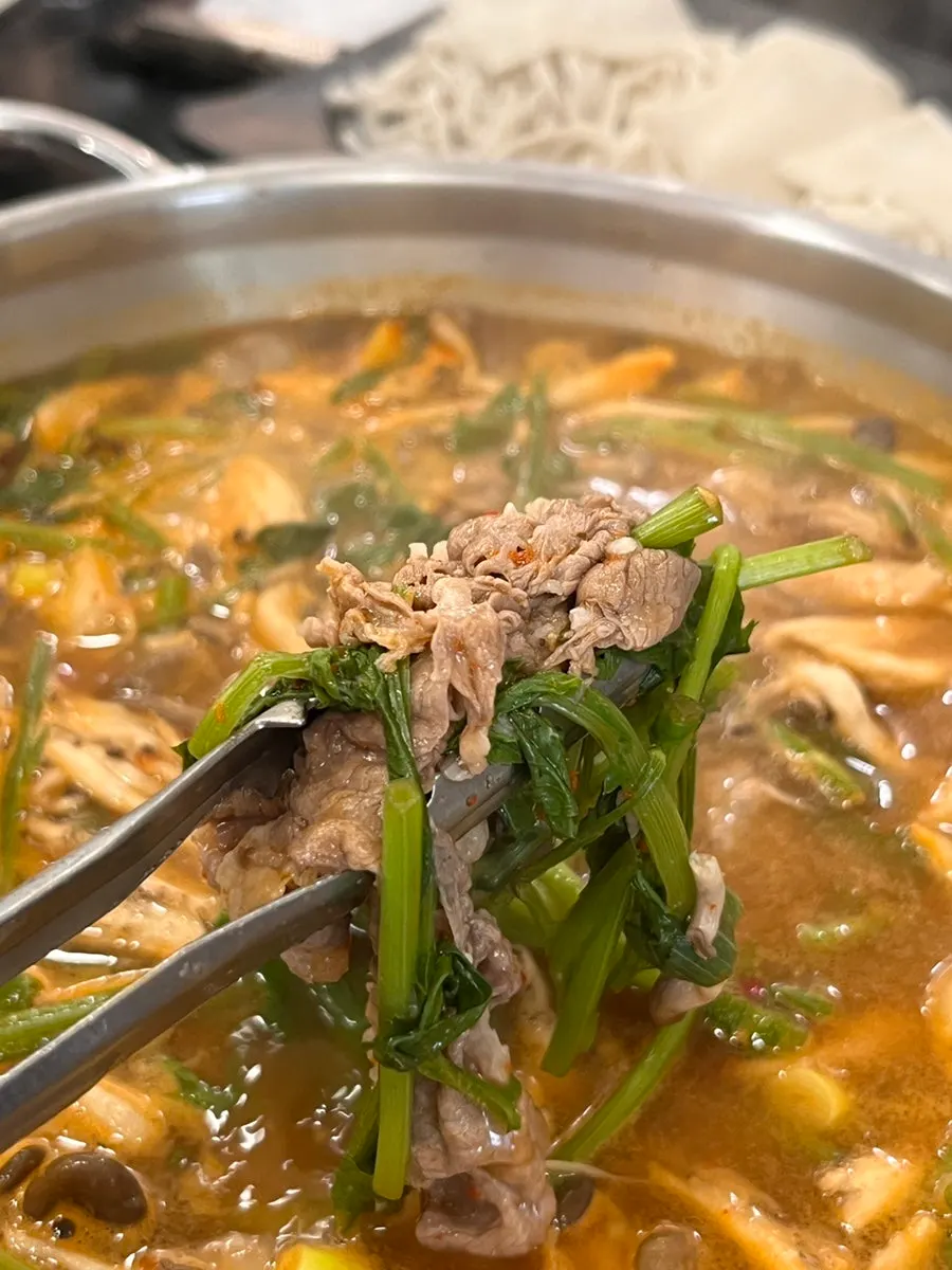 Meat, mushrooms, and minari cooking in the broth