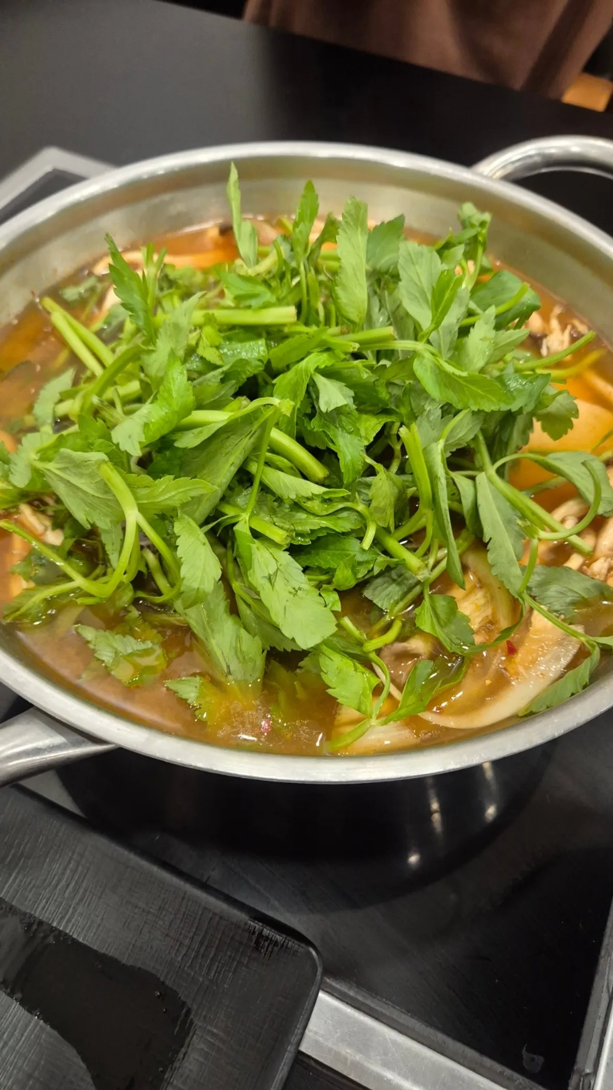 Red shabu-shabu broth loaded with vegetables and mushrooms