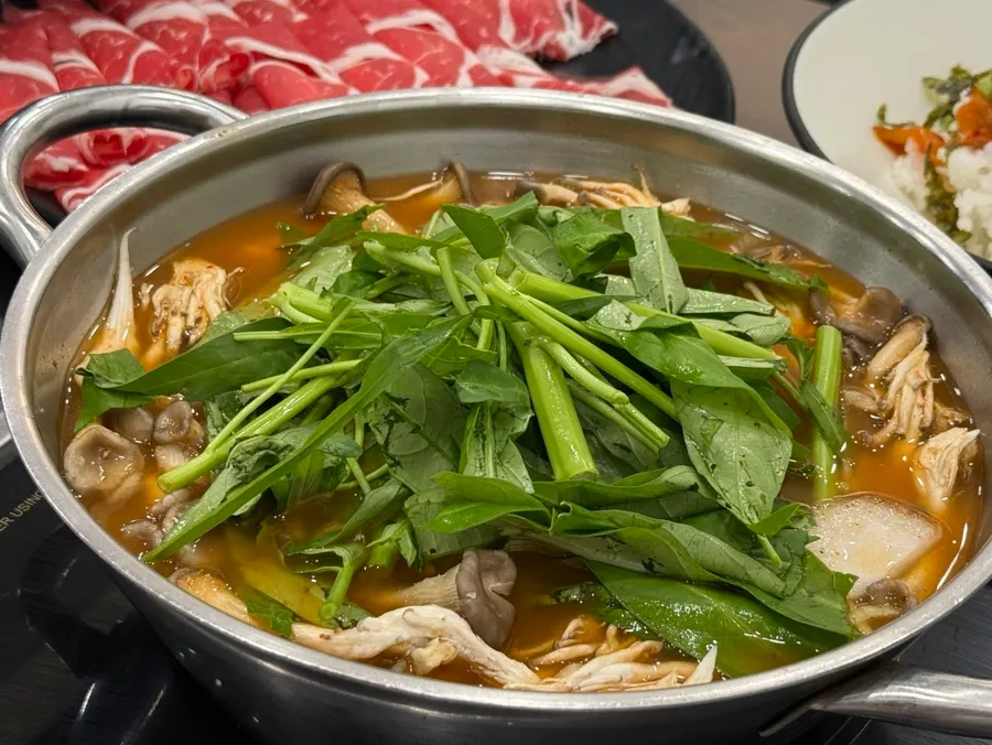 느타리버섯과 공심채가 담긴 빨간 샤브 육수 냄비
