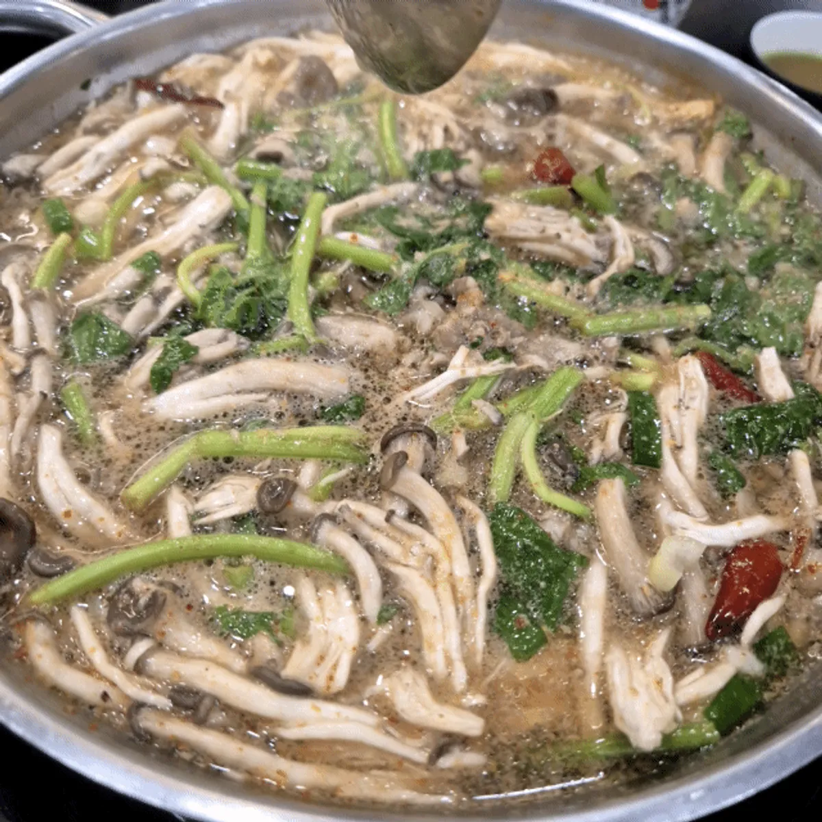 White broth with minari and mushrooms and thick shabu meat