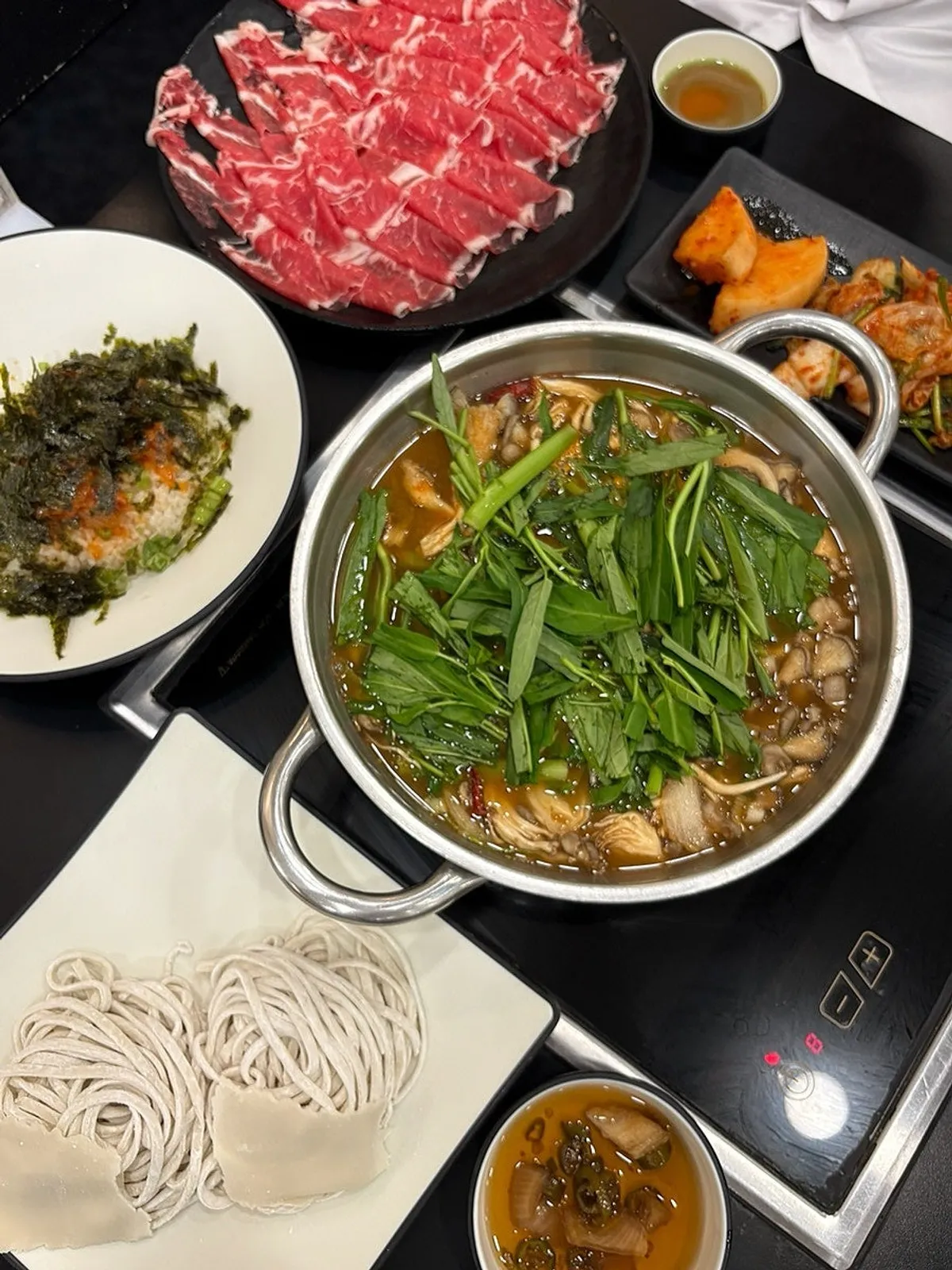 Full shabu kalguksu table spread with a pot of red broth