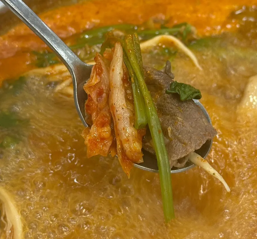 Red shabu-shabu pot piled with meat
