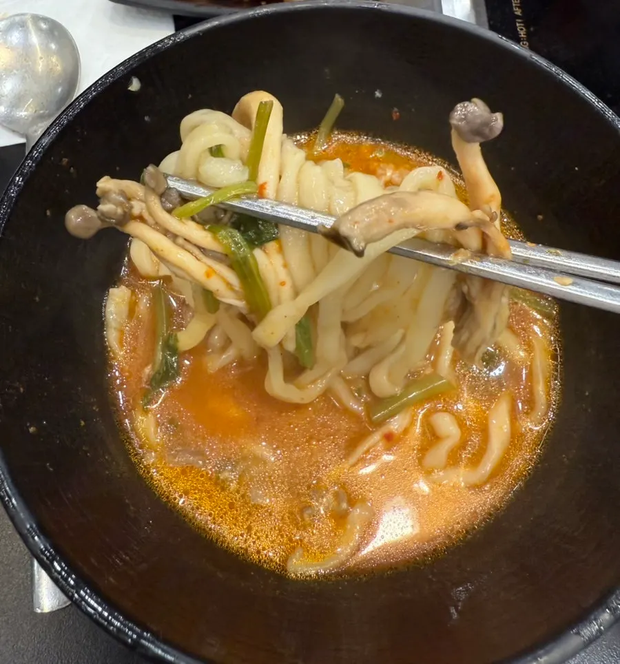 Springy kalguksu noodle strands lifted from the pot