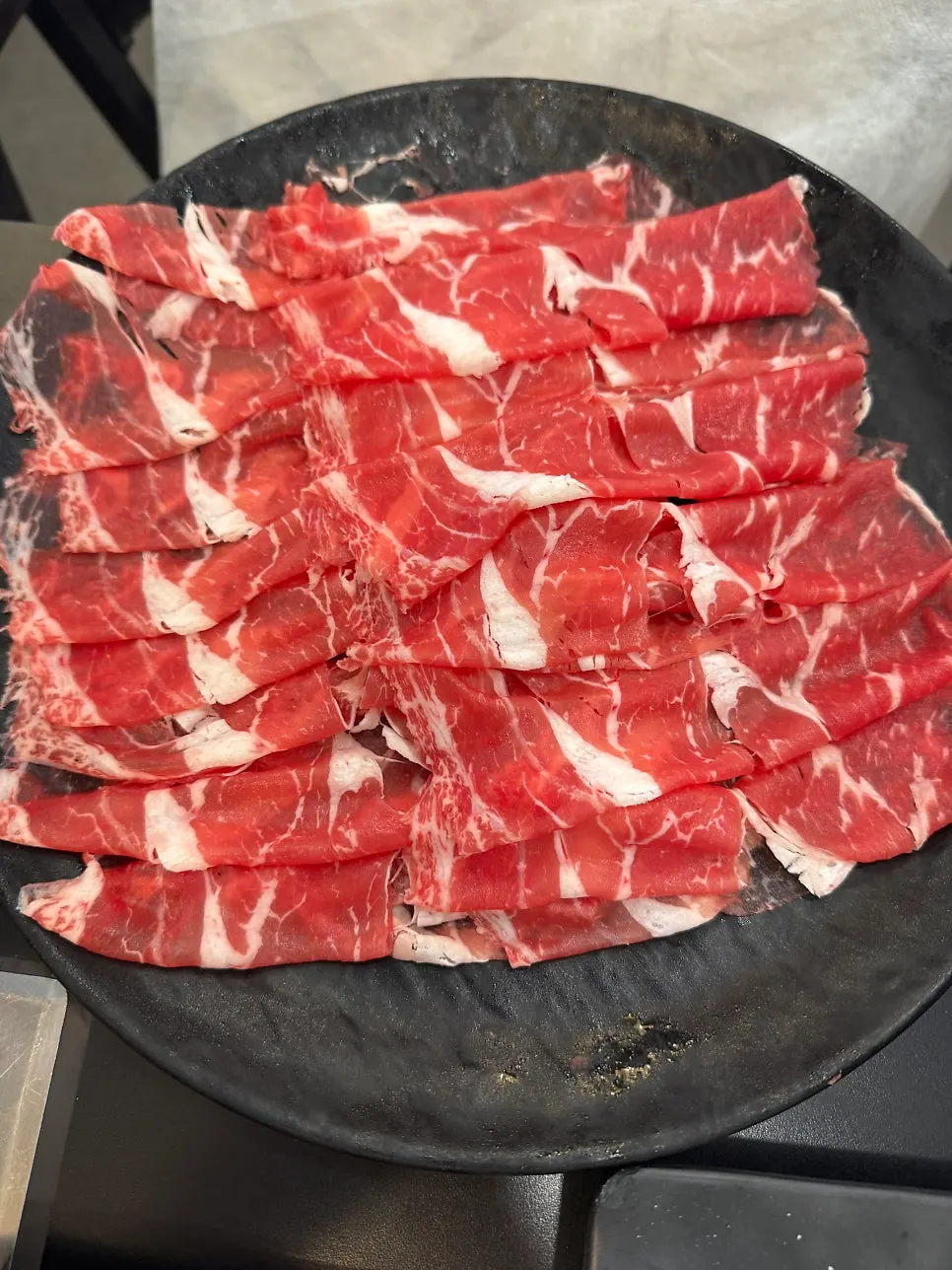 煮立った赤いだしに具材を入れる様子