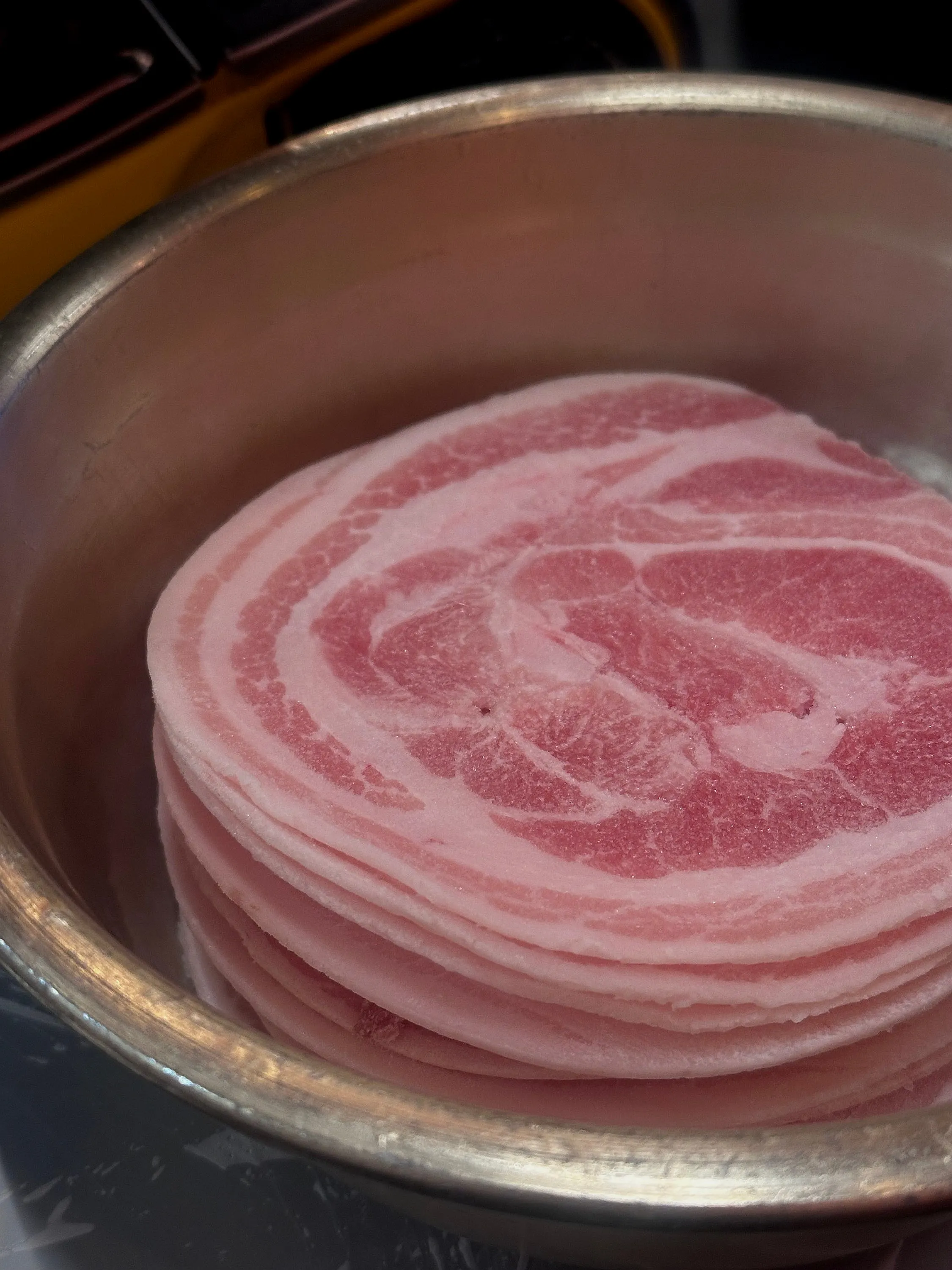Frozen pork belly cooking on a grill