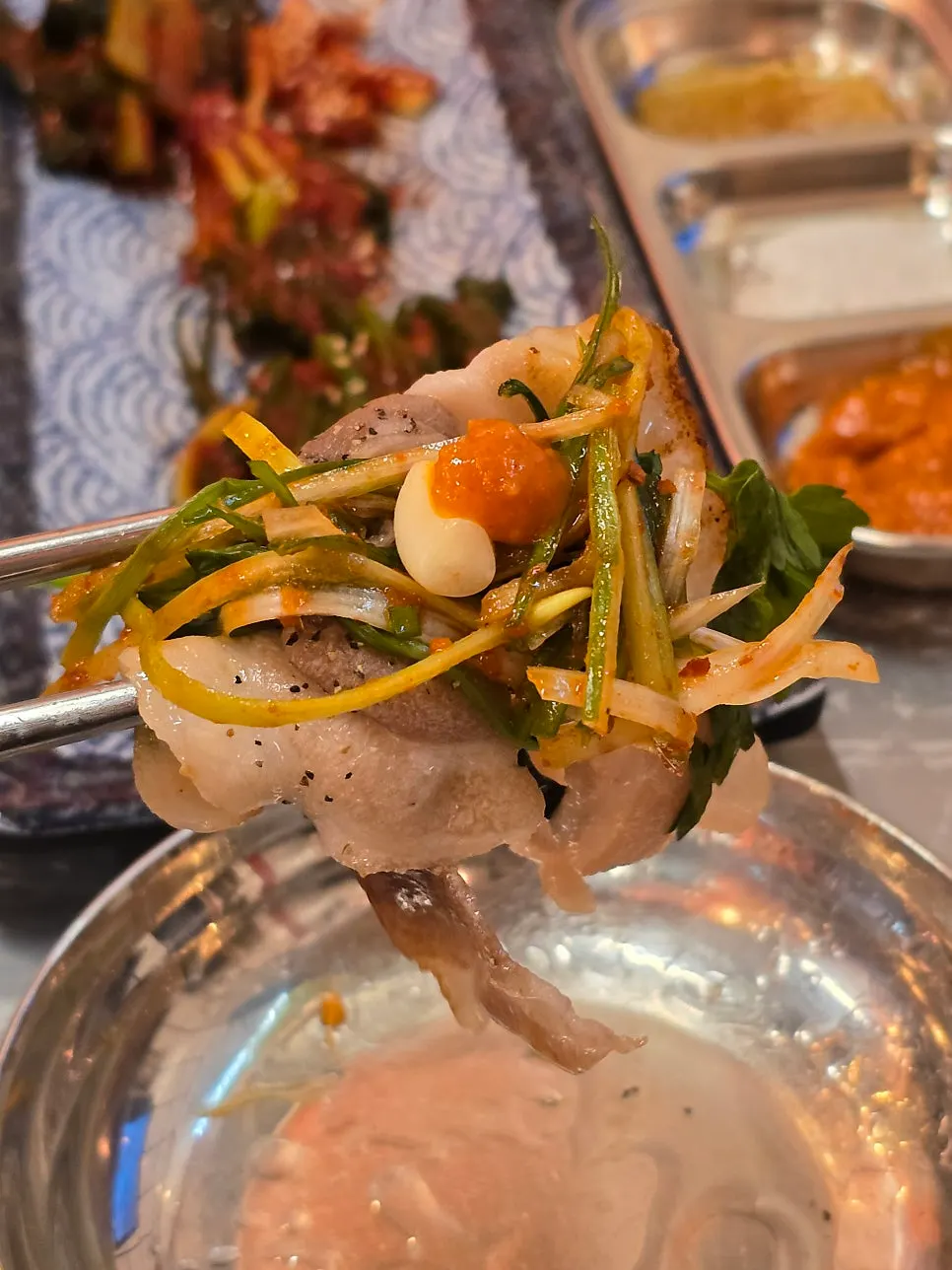 A piece of naengsam topped with green onion kimchi