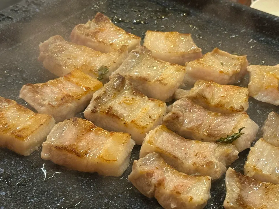 Thick fresh pork belly cooking on the grill