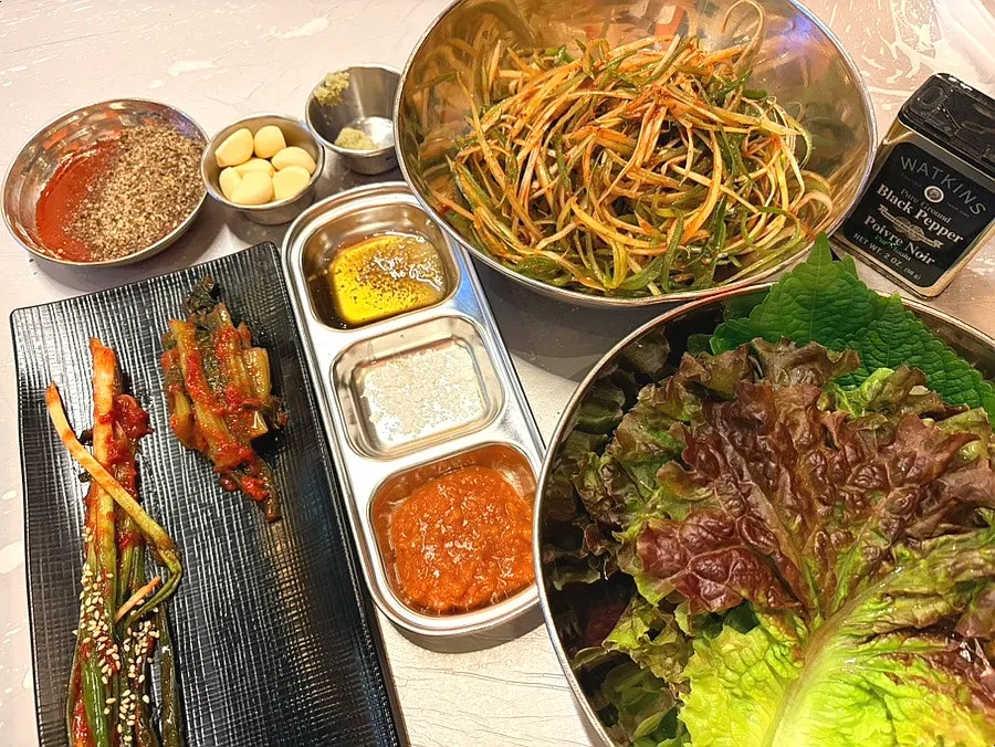 Basic banchan spread including scallion salad and mustard leaf kimchi