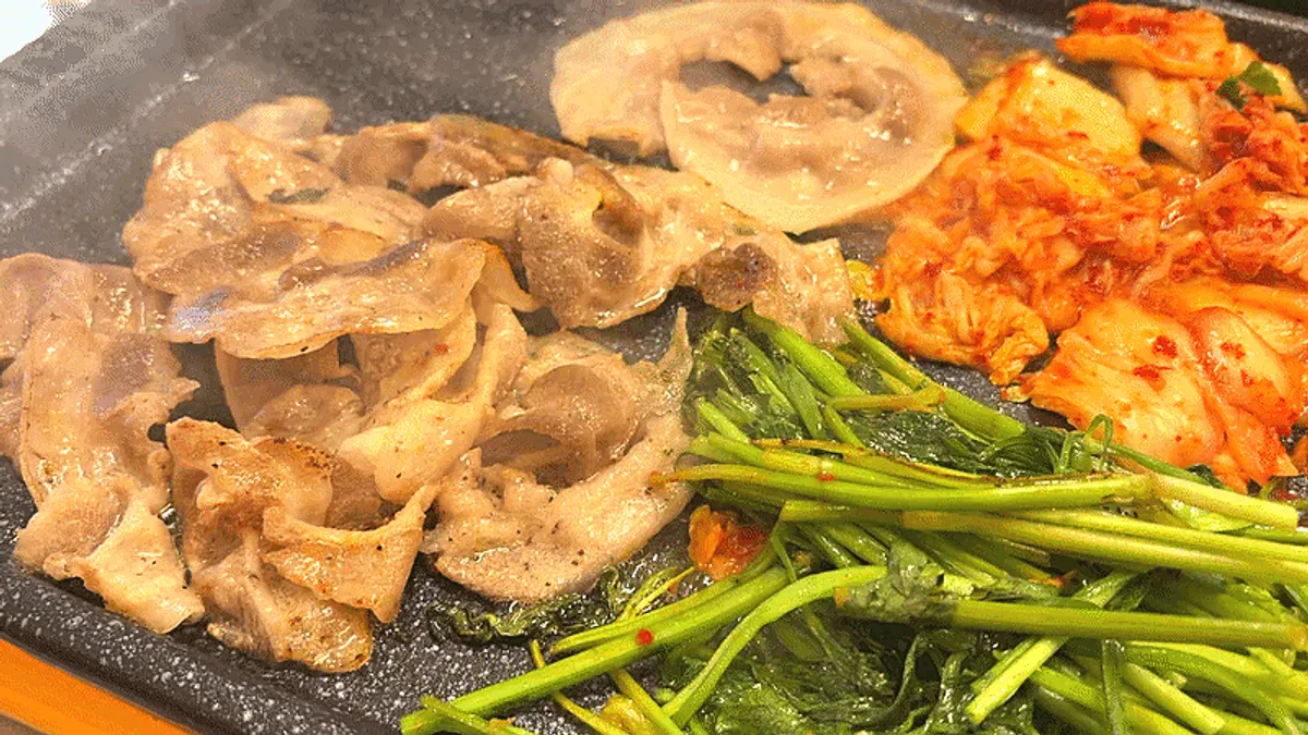A bite of flower naengsam topped with minari and kimchi