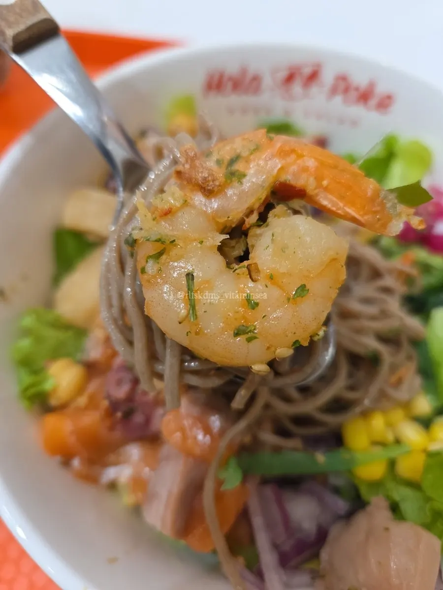 A bowl of poke with buckwheat noodles and toppings mixed together
