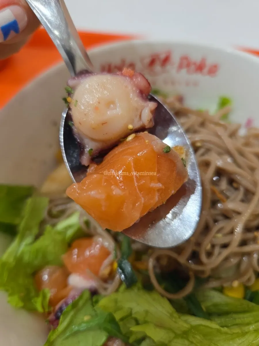A bite of poke piled with every kind of seafood