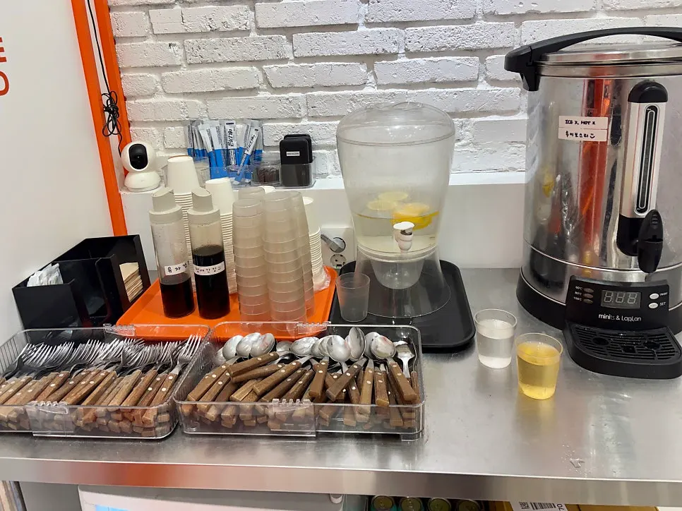 Self-service corner with utensils, water, sauces and tea