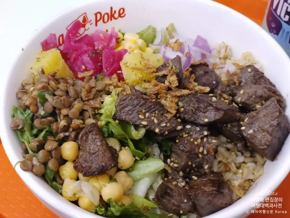 A poke bowl with steak on top of rice and salad