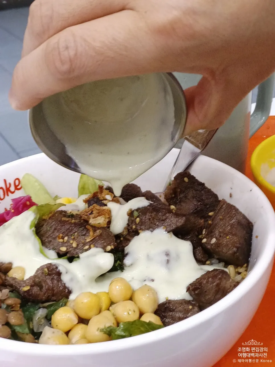 Vertical photo of the mixed steak poke after adding sauce