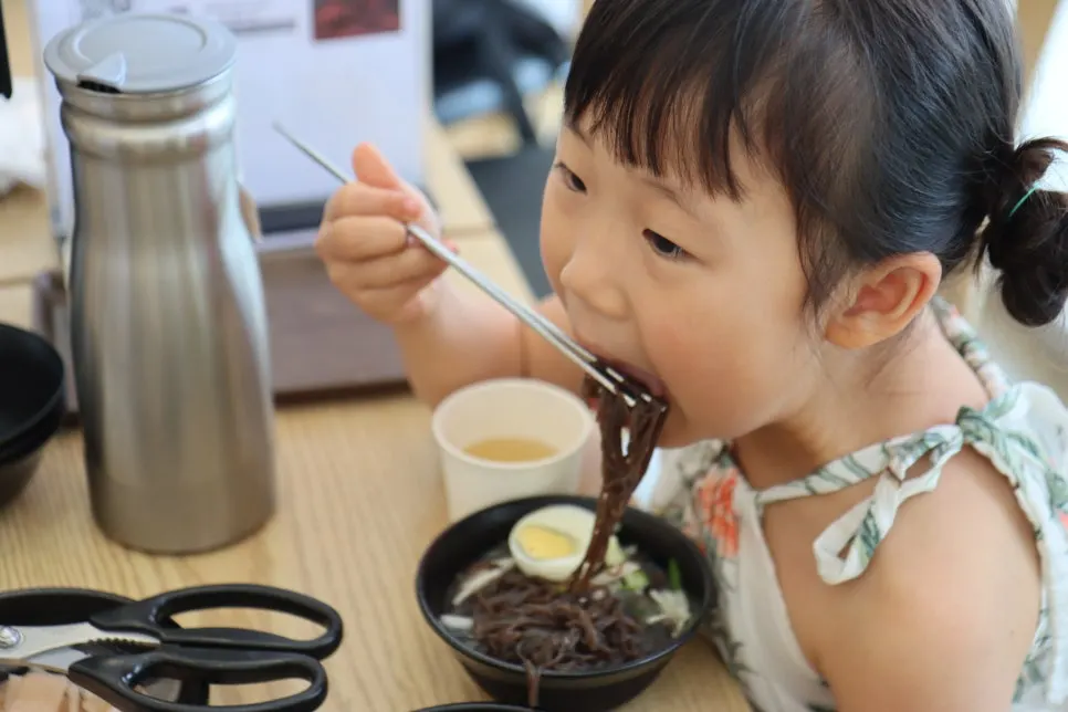 Naengmyeon noodles being lifted up with chopsticks