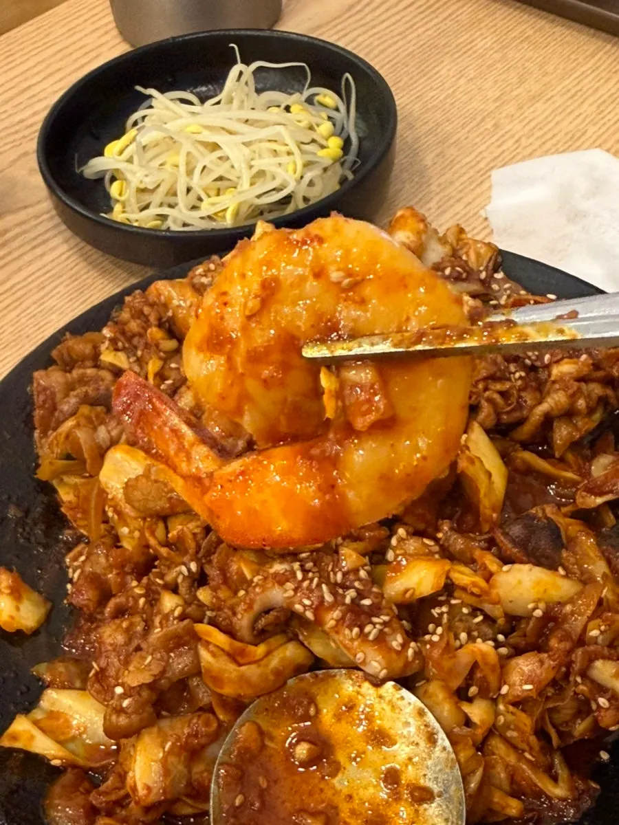 Close-up of jjukkumi stir-fry topped with large shrimp