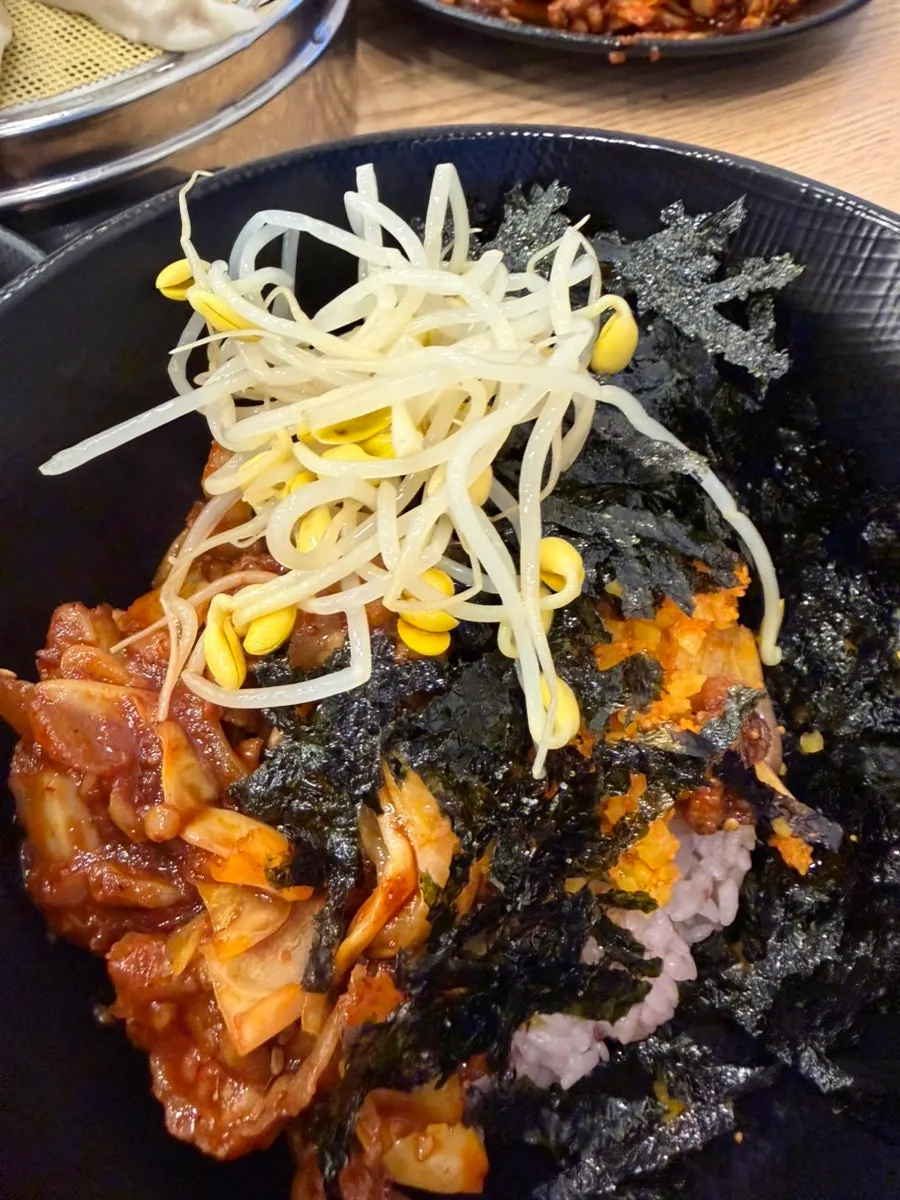 Picking up a bite of jjukkumi, pork belly, and shrimp