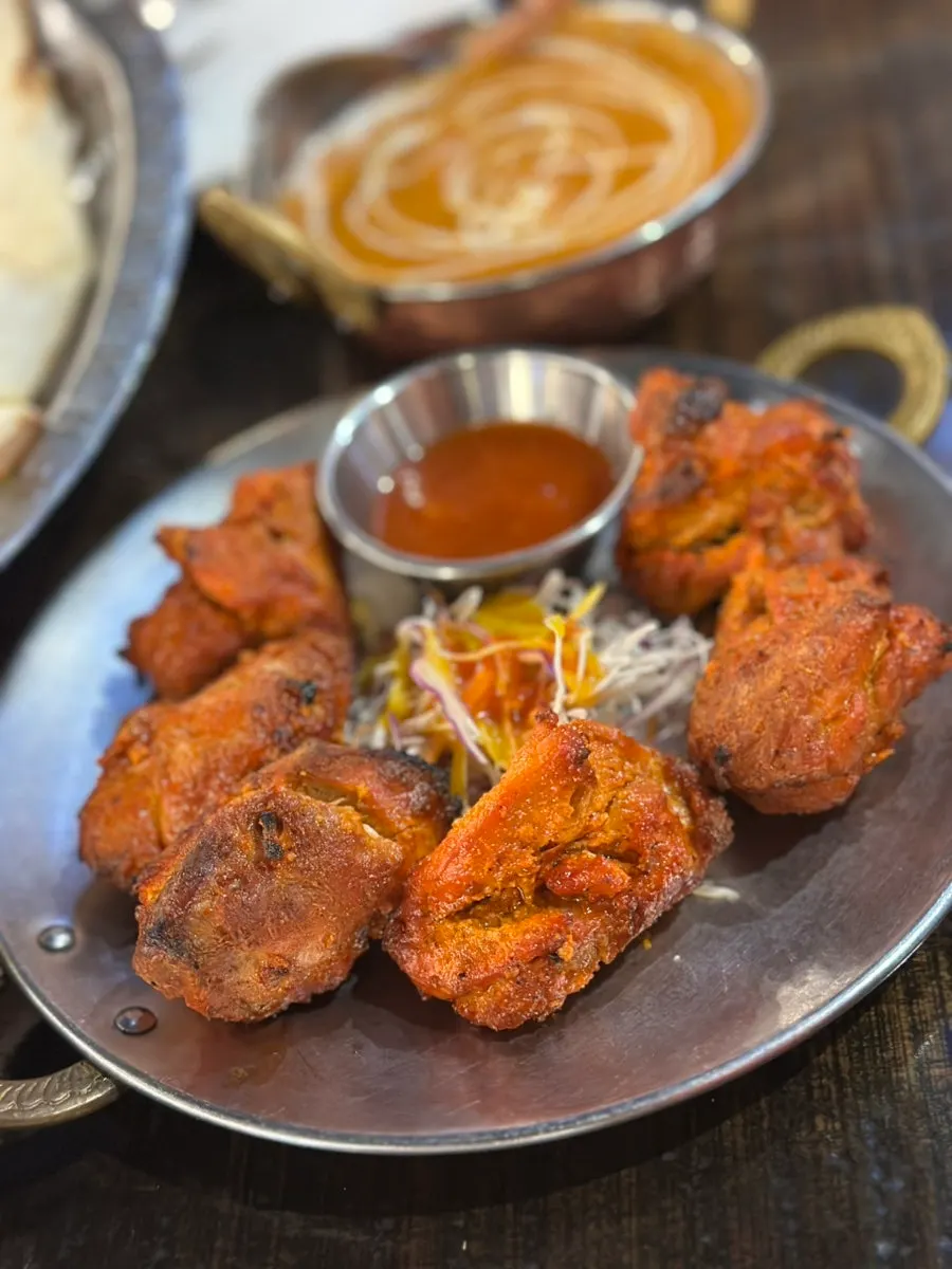 Freshly baked original naan being dipped in curry