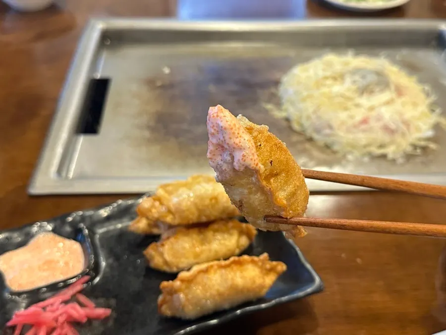 Dipping mentaiko gyoza into the cod roe sauce