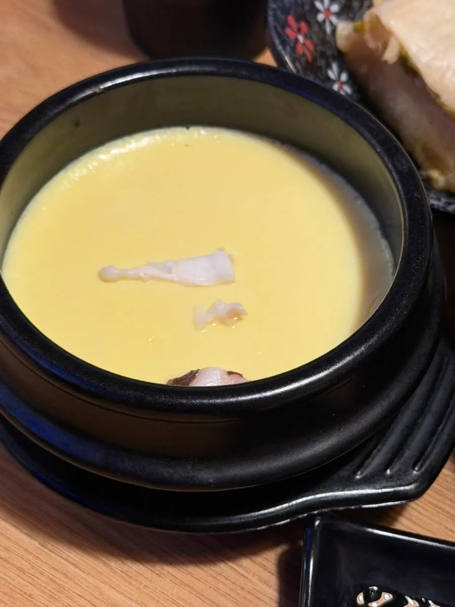 A spoonful of steamed egg with pieces of octopus inside