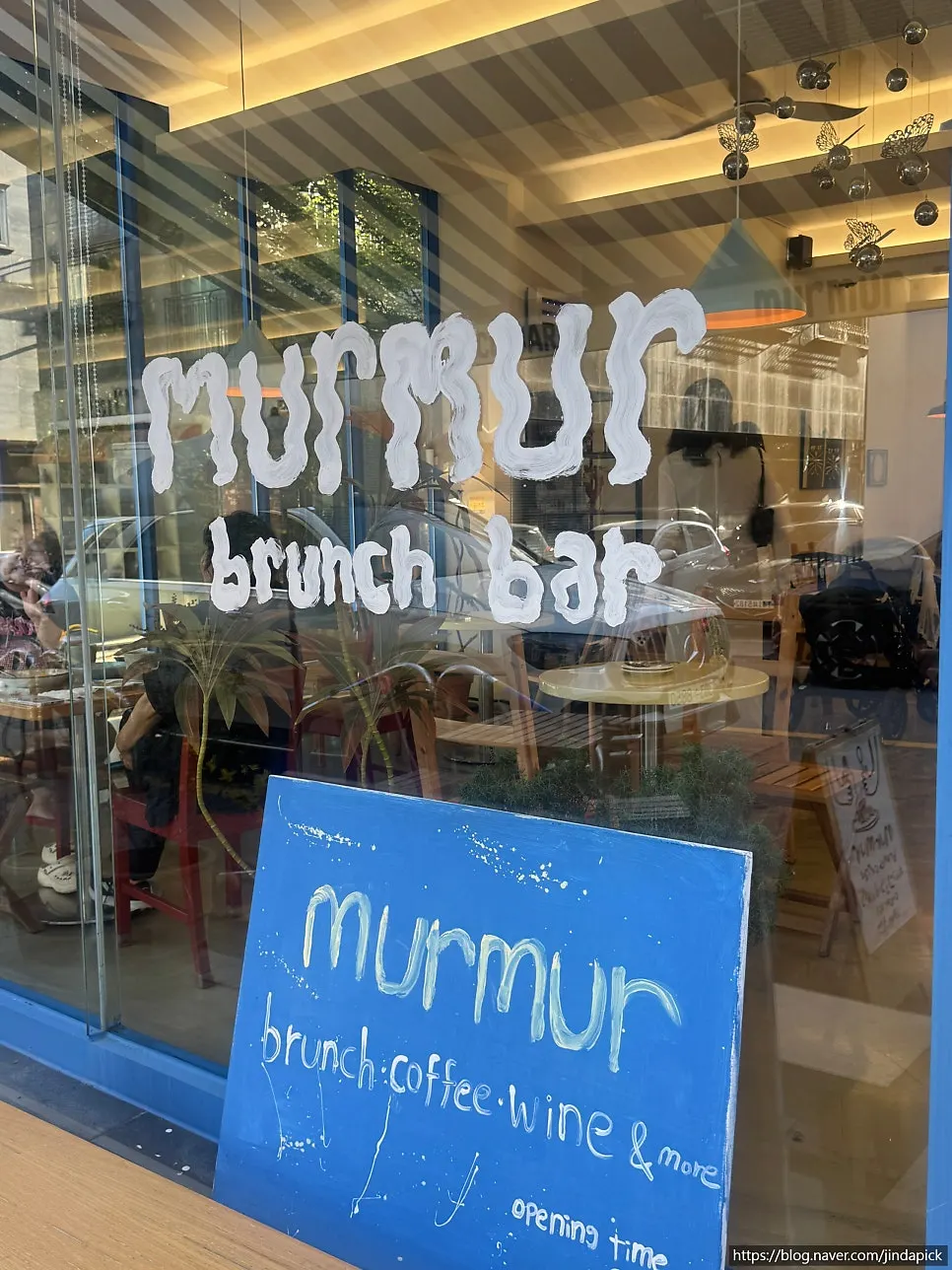 Facade with blue-striped awning and "murmur" lettering