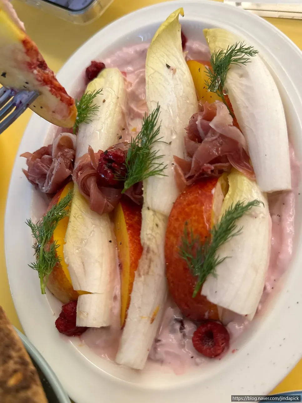 Endive salad topped with peach and prosciutto
