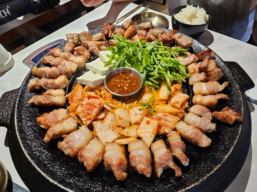 Aged kimchi, minari, and tofu piled in the center of the cast-iron plate