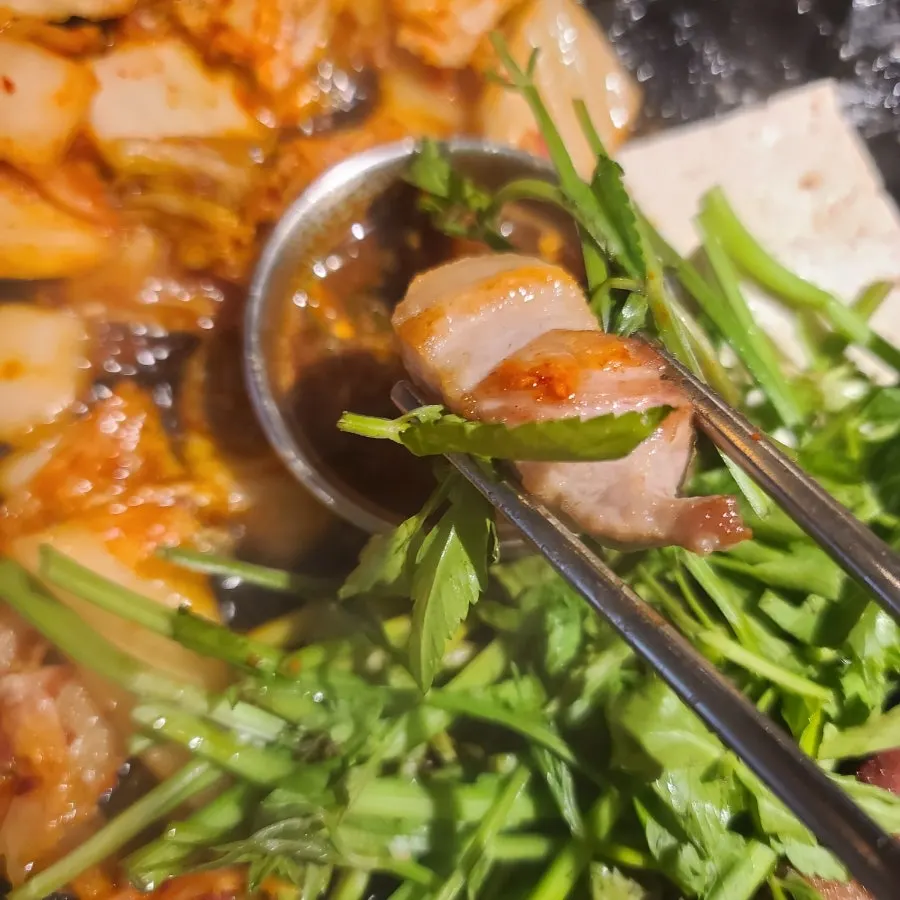 Cast-iron plate with pork belly grilled alongside minari